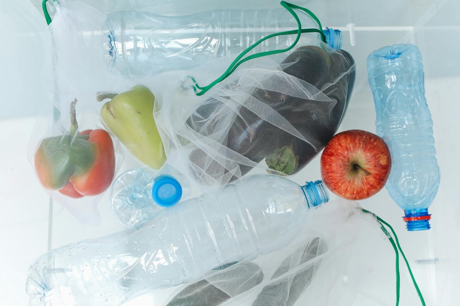Plastic bottles and vegetables in reusable mesh bags promote eco-friendly shopping.